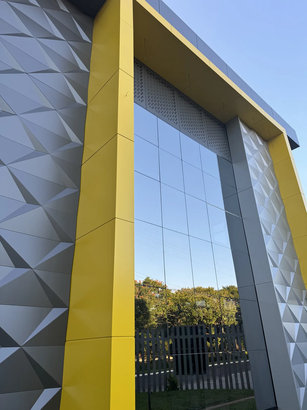 Entrance framed in yellow ACM with 3D pyramid-pattern panels on both sides