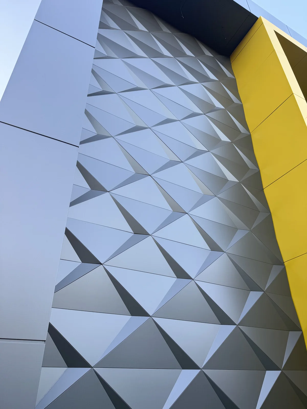 Close view of pyramid-pattern 3D ACM panels meeting a yellow ACM return