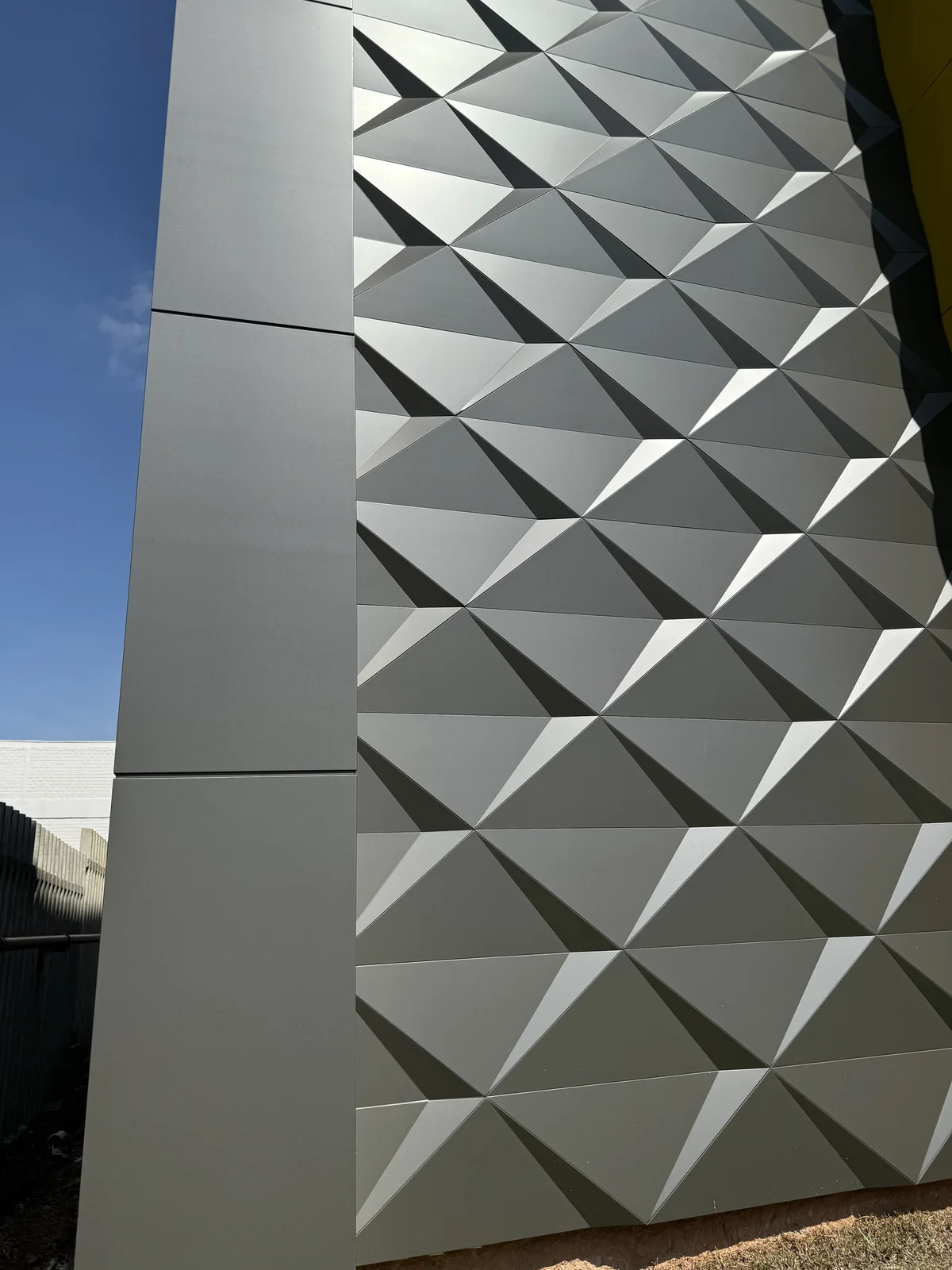 Gray 3D ACM panels with a pyramid pattern next to flat ACM panels