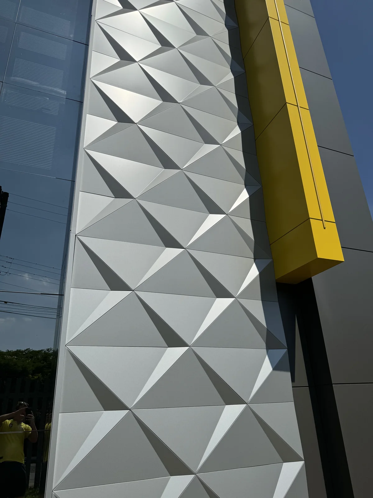 Tall wall of silver 3D ACM panels with sharp, even shadow lines