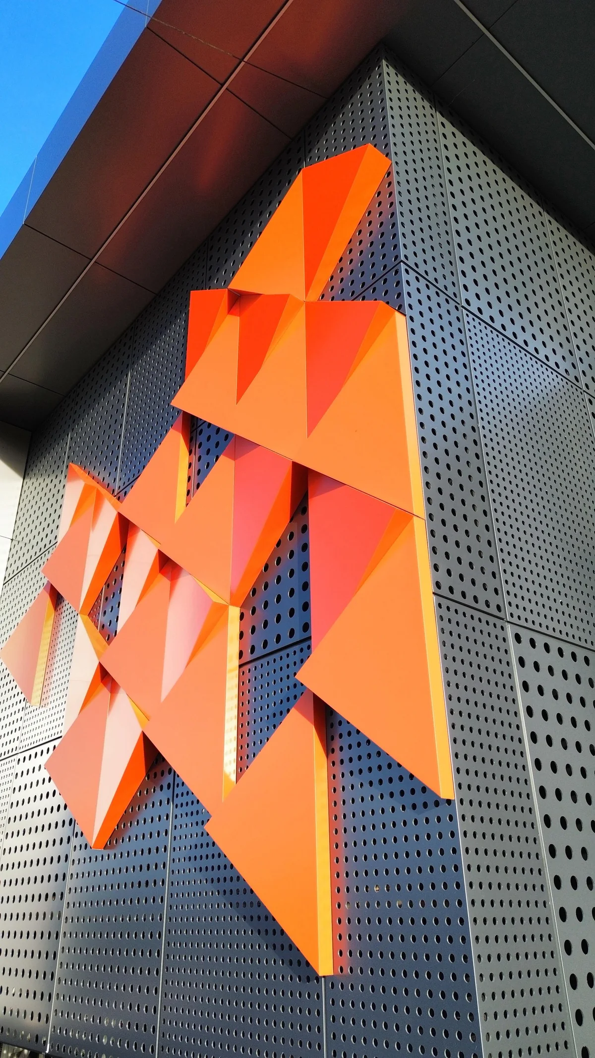 Orange three-dimensional ACM accent pieces on a perforated ACM facade