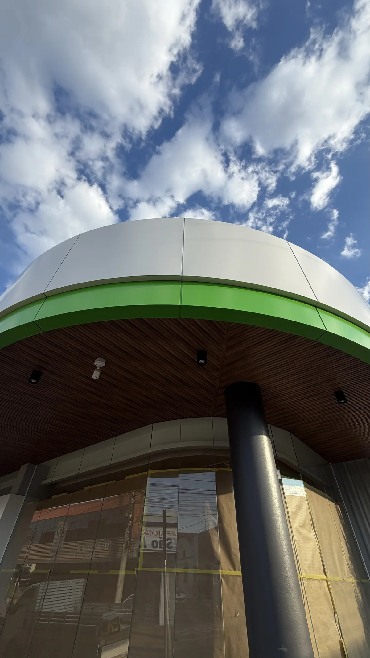 Close view of the curved white and green ACM band and soffit around a dark column