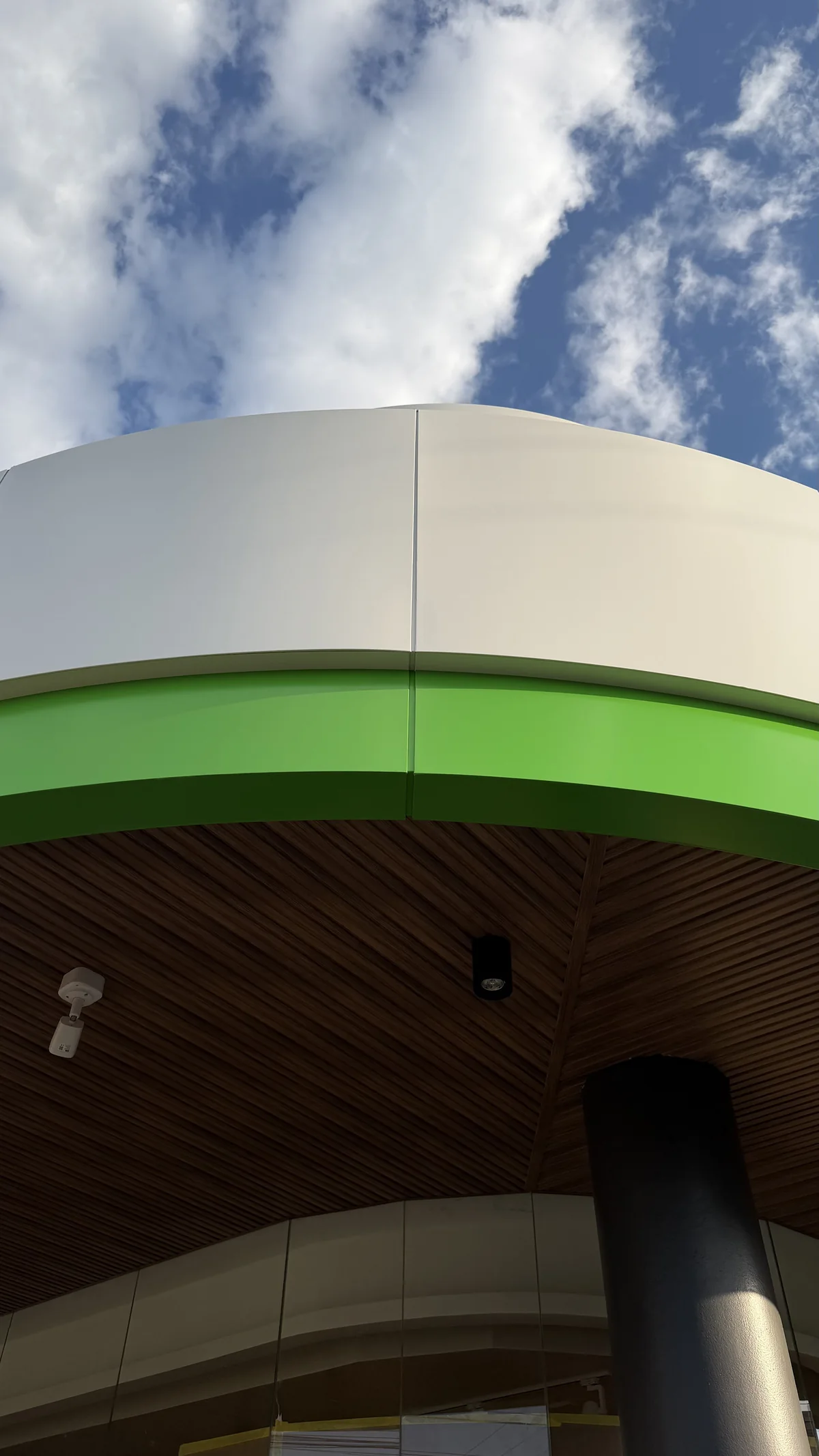 Curved white and green ACM panels with precise joints seen from below