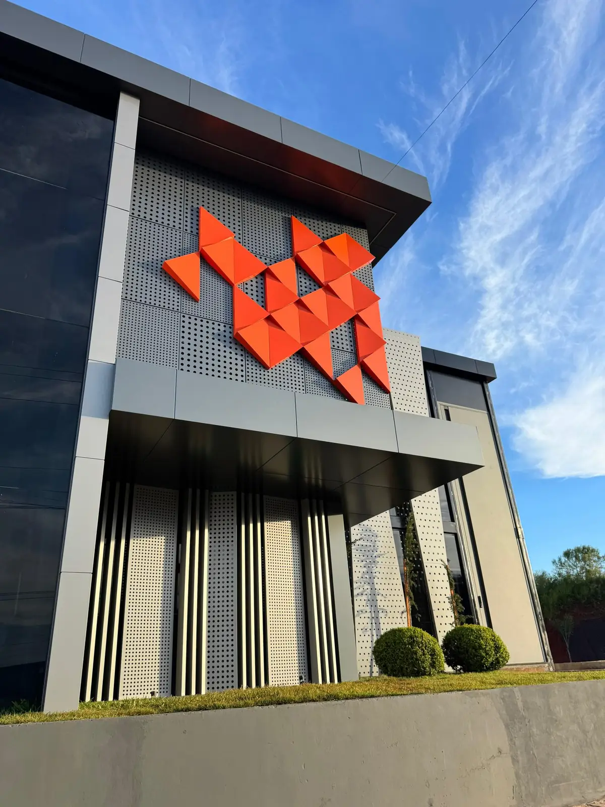 Perforated ACM facade with orange geometric accent pieces