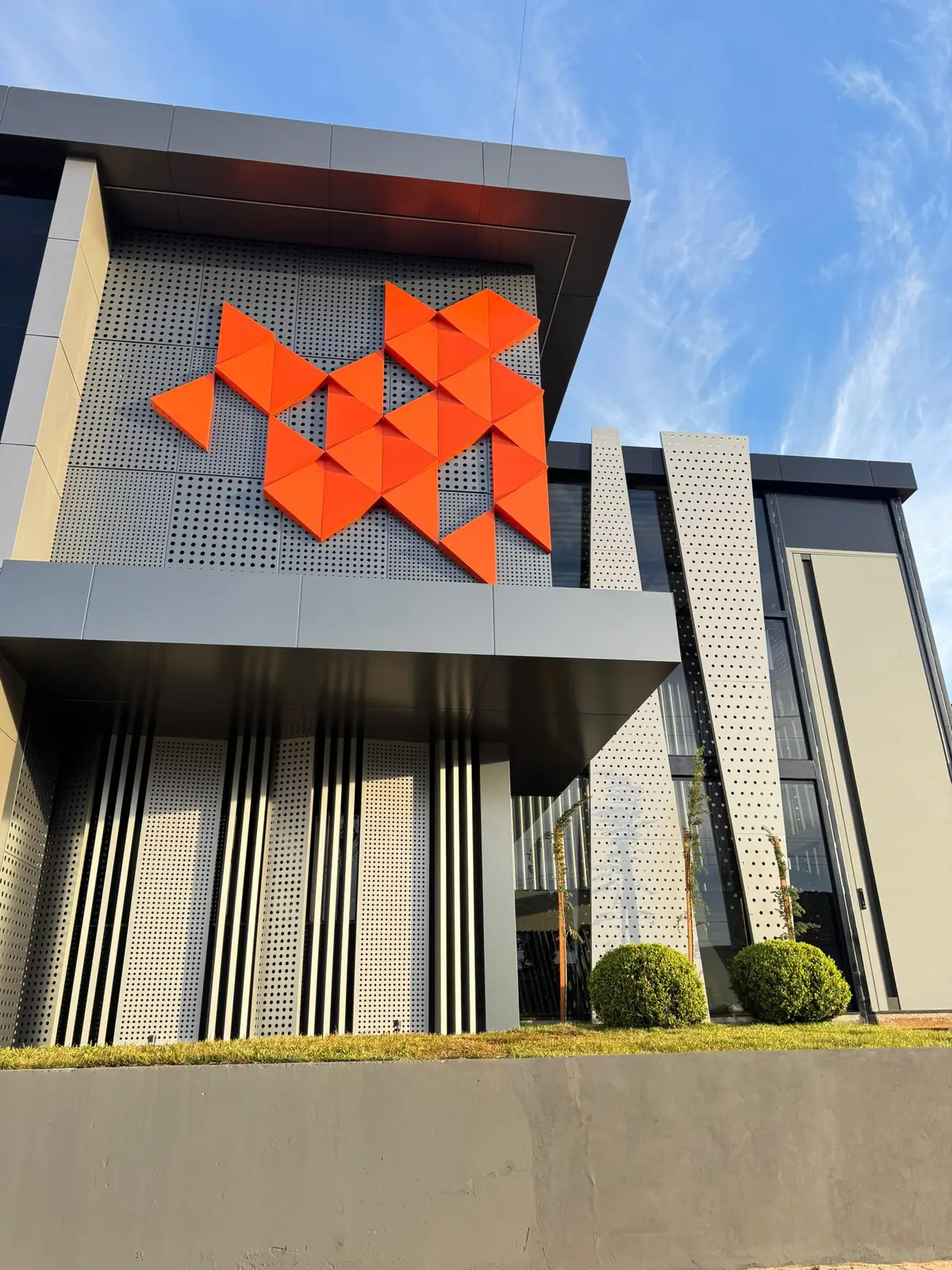 Orange geometric ACM accents on a perforated facade