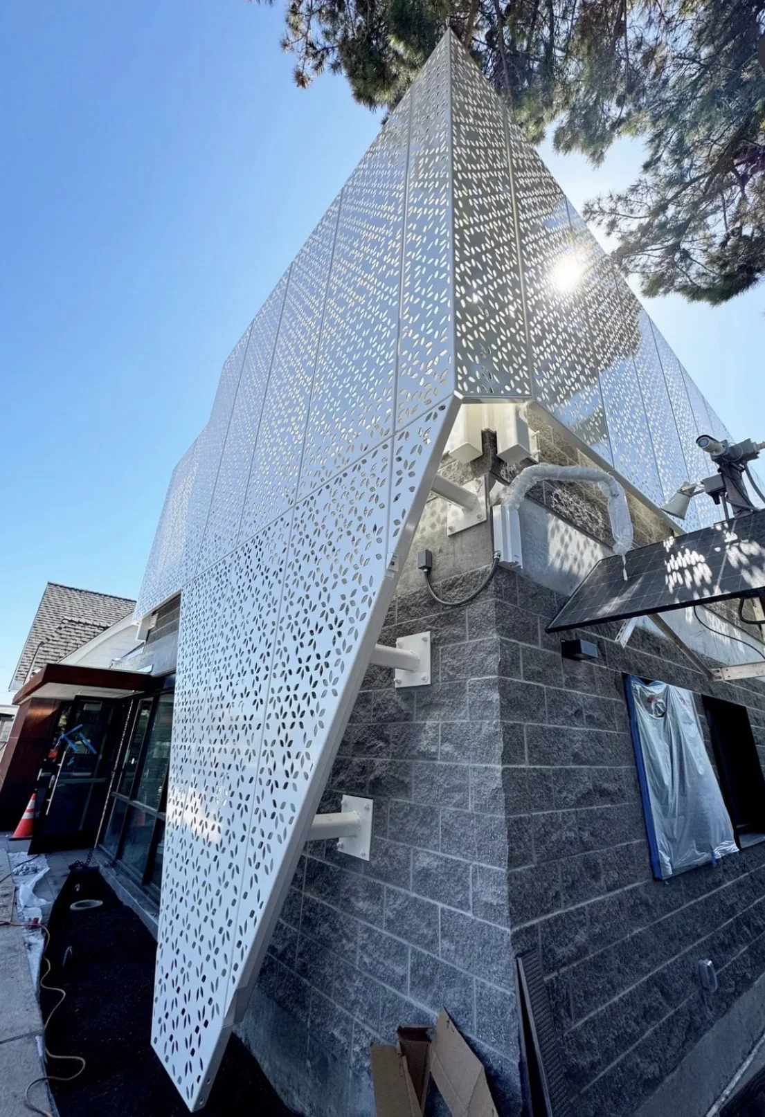 Faceted perforated panel with an intricate pattern on a building corner