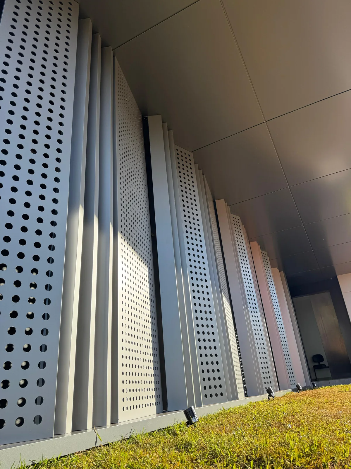 Row of tall perforated ACM fins with different hole sizes along a walkway