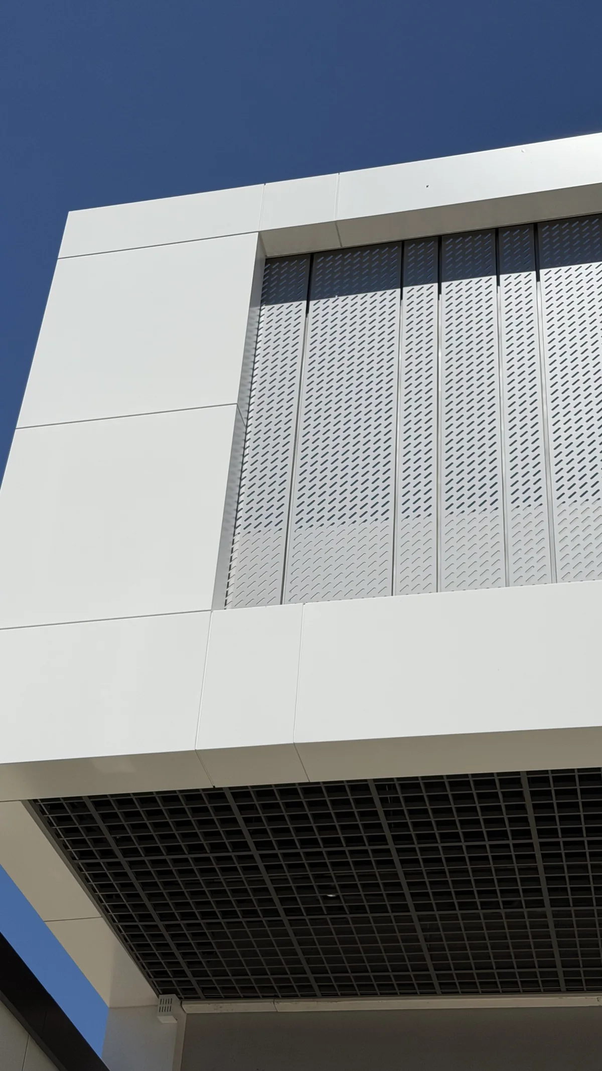 Slotted perforated ACM screen inside a white ACM frame above a grid ceiling